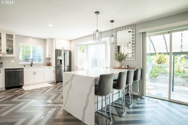 kitchen with appliances with stainless steel finishes, dark parquet flooring, tasteful backsplash, sink, and white cabinets