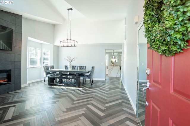 dining room featuring a fireplace, dark parquet floors, and a high ceiling