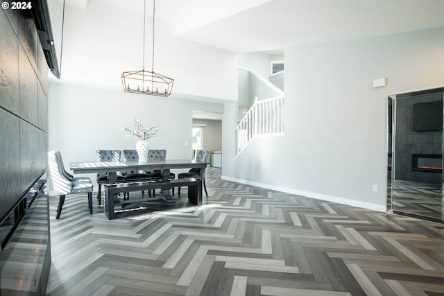 dining room featuring dark parquet floors, a towering ceiling, and a fireplace