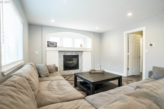 living room featuring parquet flooring and a stone fireplace