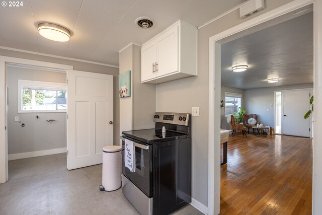 kitchen featuring white cabinets, ornamental molding, stainless steel electric range oven, and light hardwood / wood-style floors