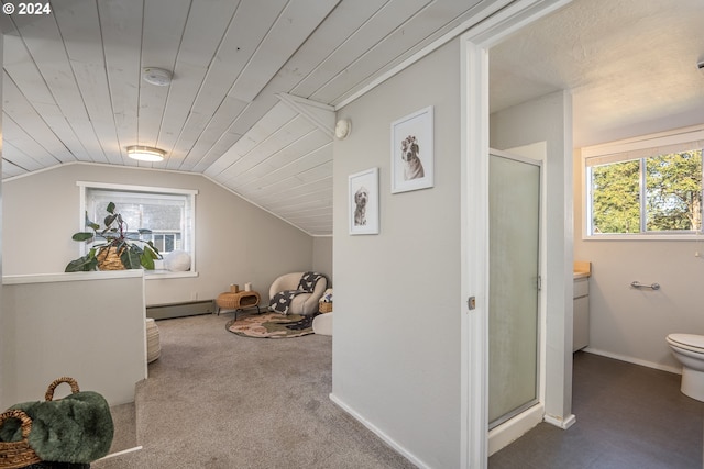 interior space featuring a baseboard heating unit, a wealth of natural light, lofted ceiling, and carpet floors