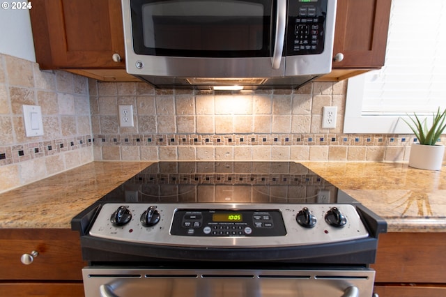 kitchen with light stone countertops, tasteful backsplash, and range