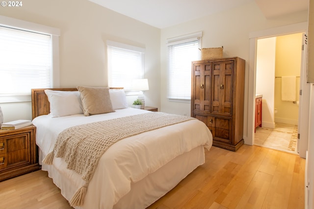 bedroom featuring ensuite bath and light hardwood / wood-style floors