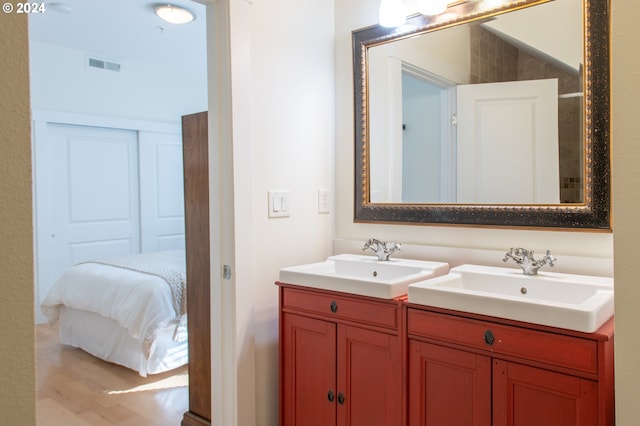 bathroom featuring vanity with extensive cabinet space, hardwood / wood-style flooring, and double sink