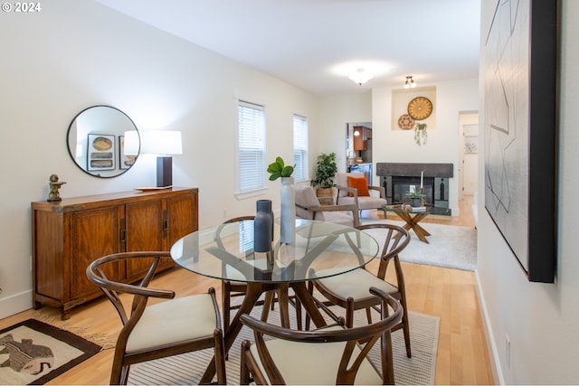 dining space featuring light wood-type flooring and a multi sided fireplace