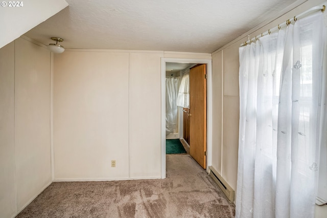 empty room featuring light carpet, a textured ceiling, and a baseboard heating unit