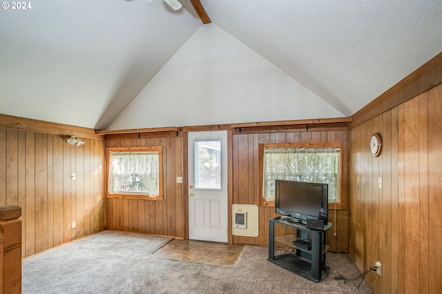 carpeted foyer entrance featuring wooden walls, vaulted ceiling with beams, and heating unit