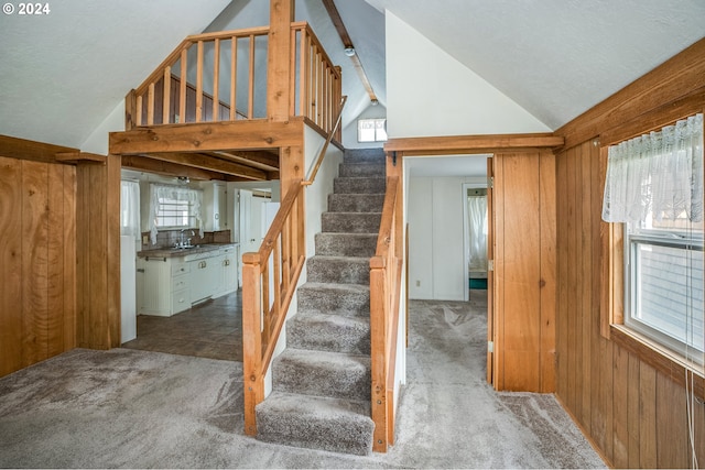 stairway featuring carpet floors, lofted ceiling, wood walls, and sink