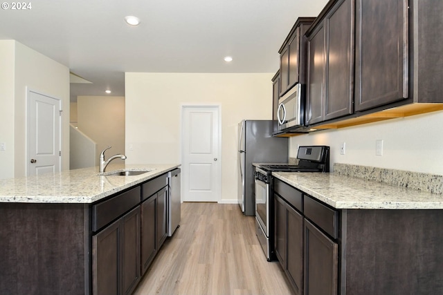 kitchen with dark brown cabinetry, light stone countertops, sink, appliances with stainless steel finishes, and light wood-type flooring