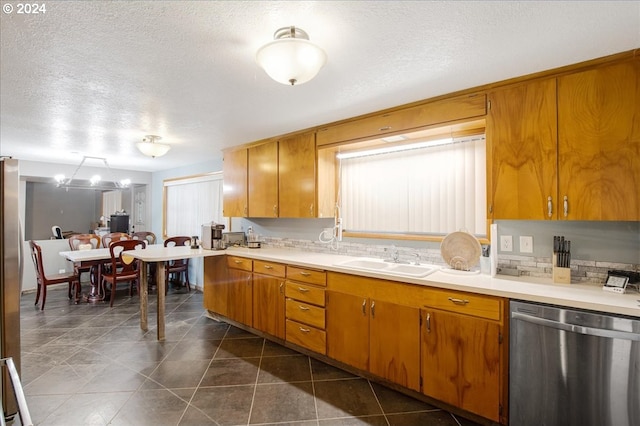 kitchen featuring stainless steel dishwasher, dark tile patterned floors, sink, and a textured ceiling