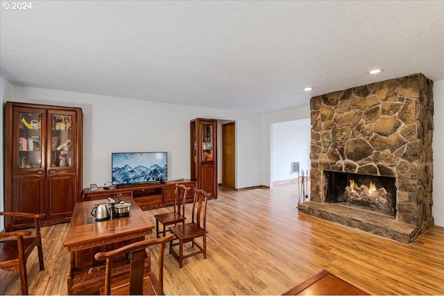 dining area with a fireplace, a textured ceiling, and light wood-type flooring