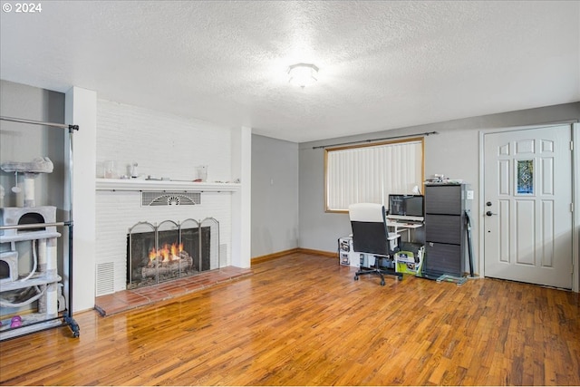 office featuring a fireplace, hardwood / wood-style floors, and a textured ceiling