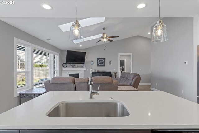 kitchen featuring a fireplace, ceiling fan, an island with sink, and sink