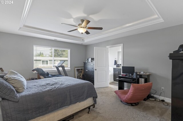 bedroom featuring a raised ceiling, ceiling fan, ensuite bathroom, and light colored carpet