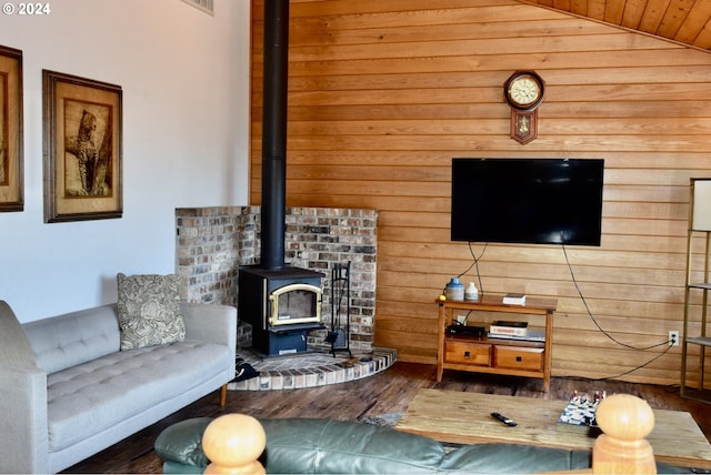 living room featuring a wood stove, wooden walls, hardwood / wood-style floors, and lofted ceiling