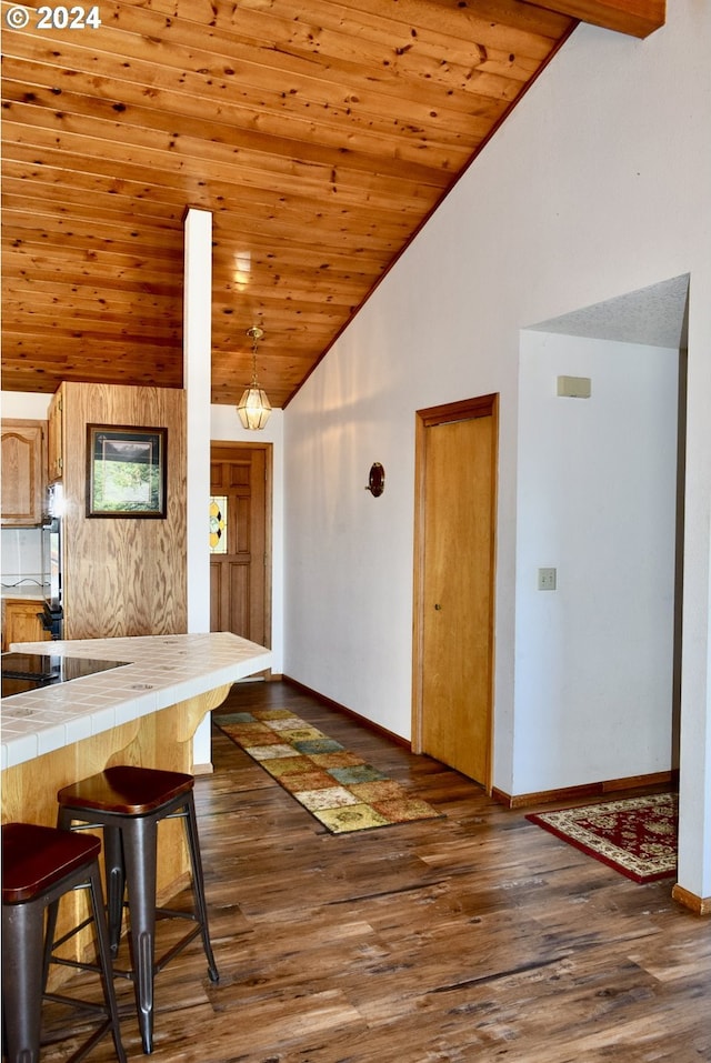 kitchen featuring a kitchen breakfast bar, tile counters, wood ceiling, and dark hardwood / wood-style floors