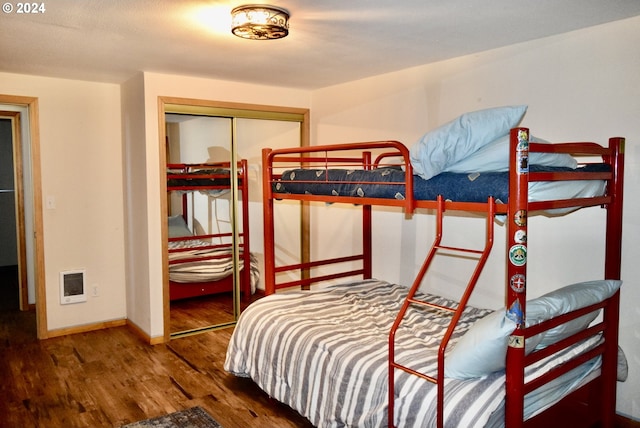 bedroom with heating unit, wood-type flooring, and a closet