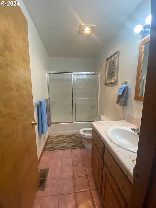 full bathroom featuring combined bath / shower with glass door, vanity, tile patterned floors, and toilet