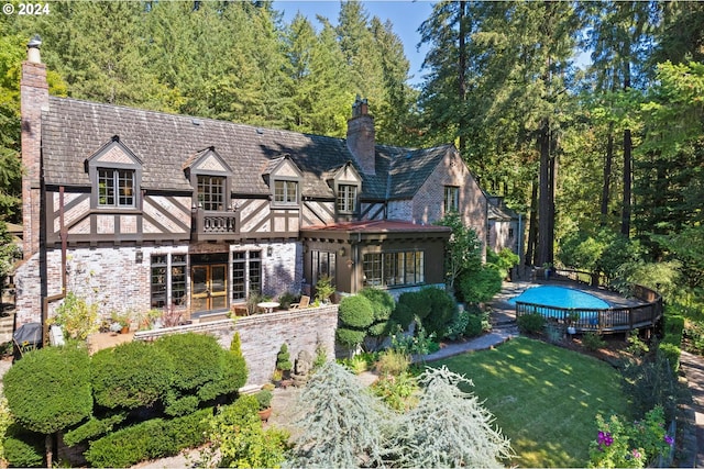 rear view of property with french doors, brick siding, an outdoor pool, and a chimney