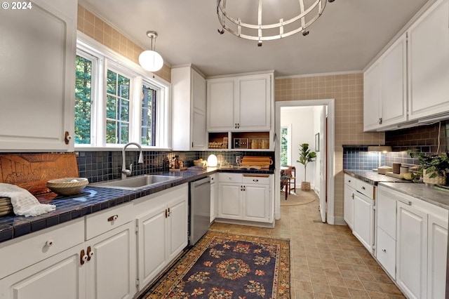 kitchen with tile counters, decorative backsplash, white cabinets, a sink, and stainless steel dishwasher