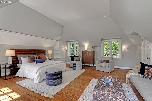 bedroom featuring lofted ceiling, baseboards, and wood finished floors