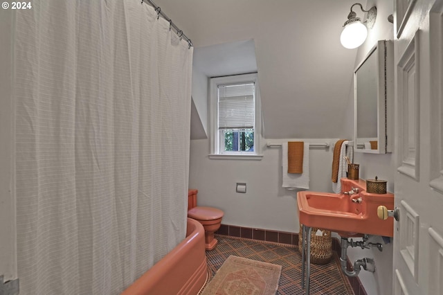 bathroom featuring toilet, shower / bath combo, a sink, baseboards, and tile patterned floors