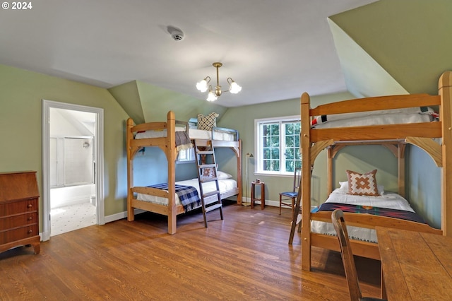 bedroom featuring lofted ceiling, connected bathroom, a notable chandelier, wood finished floors, and baseboards