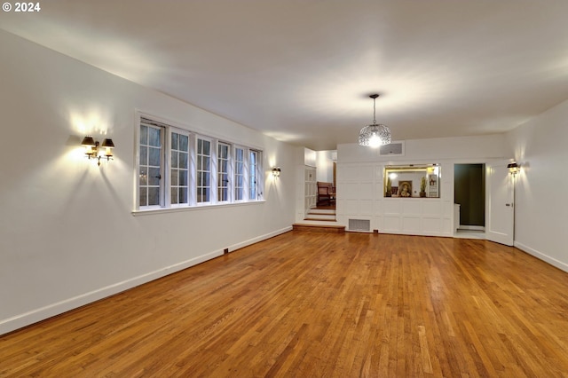 unfurnished living room with visible vents, stairs, baseboards, and wood finished floors