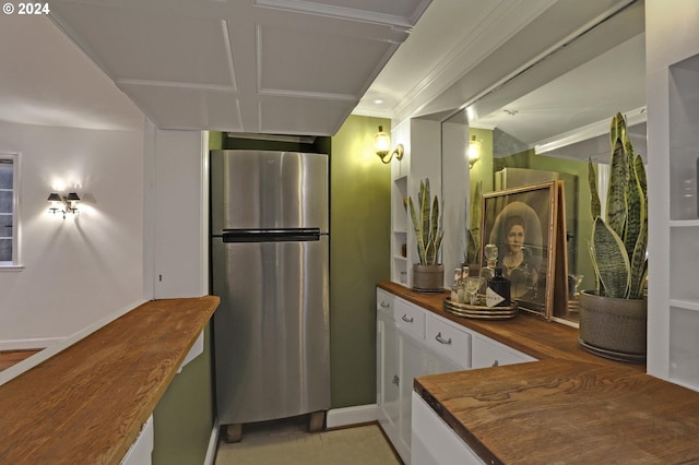 kitchen with crown molding, butcher block countertops, freestanding refrigerator, and white cabinetry