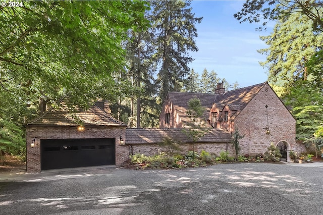 exterior space with brick siding, driveway, and a chimney