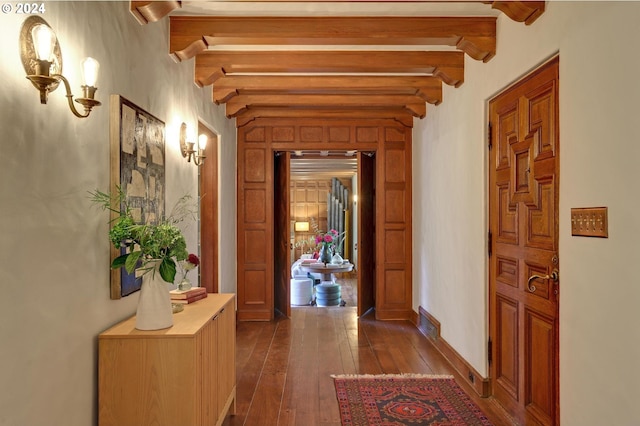 corridor featuring dark wood-style floors, visible vents, baseboards, and beamed ceiling