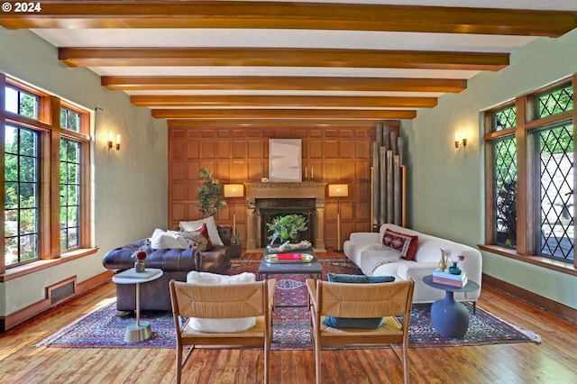 living area featuring a fireplace, wood finished floors, visible vents, baseboards, and beamed ceiling