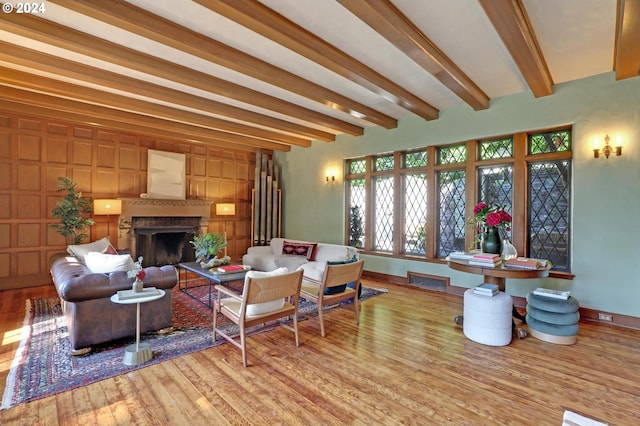 living room featuring beam ceiling, visible vents, wood finished floors, and a high end fireplace