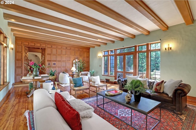 living area with beam ceiling, baseboards, and wood finished floors