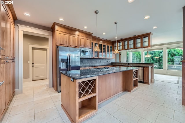 kitchen featuring stainless steel appliances, dark stone countertops, decorative backsplash, and a center island