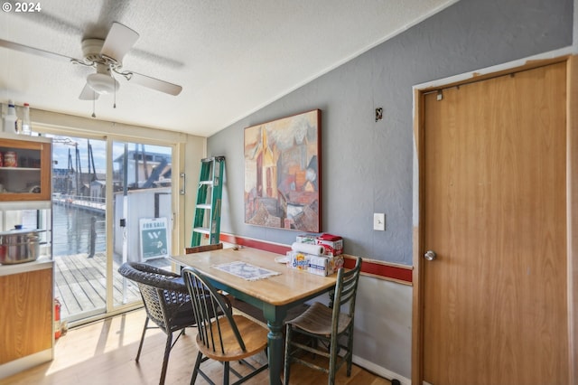 dining area featuring ceiling fan, hardwood / wood-style floors, lofted ceiling, and a textured ceiling