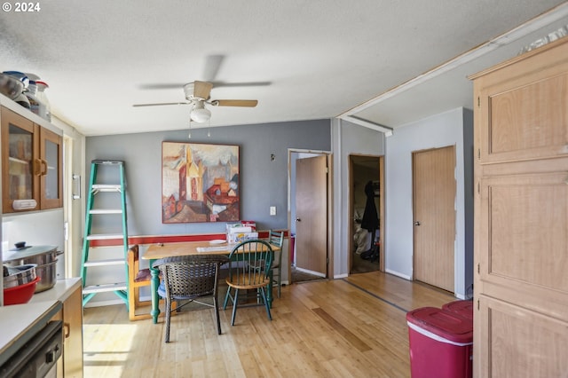 dining space featuring lofted ceiling, a textured ceiling, ceiling fan, and light hardwood / wood-style floors