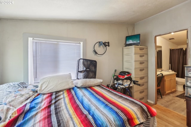 bedroom featuring connected bathroom and light hardwood / wood-style flooring