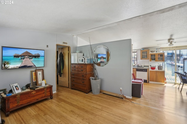 living room with light wood-type flooring, ceiling fan, vaulted ceiling, and a textured ceiling