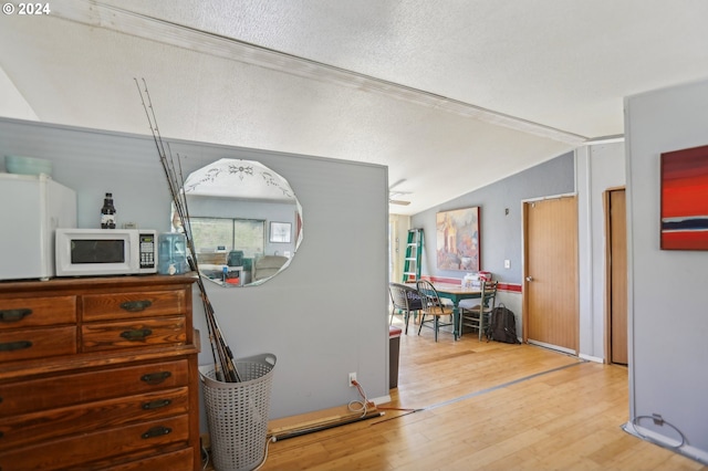 interior space featuring hardwood / wood-style flooring, a textured ceiling, ornamental molding, and vaulted ceiling