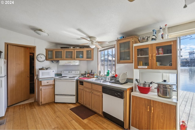 kitchen featuring white appliances, light hardwood / wood-style floors, lofted ceiling, ceiling fan, and sink