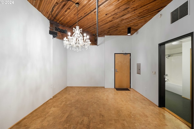 empty room with wood ceiling, light carpet, a towering ceiling, and a chandelier