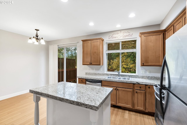 2067 NE 49th Way, Hillsboro, OR 97124 - kitchen with appliances with stainless steel finishes, a sink, light wood finished floors, brown cabinets, and a chandelier