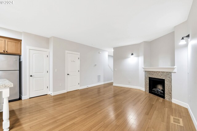 2067 NE 49th Way, Hillsboro, OR 97124 - unfurnished living room with light wood finished floors, a fireplace, and baseboards
