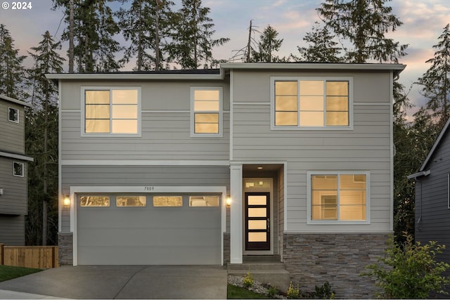 contemporary home with an attached garage, stone siding, and concrete driveway