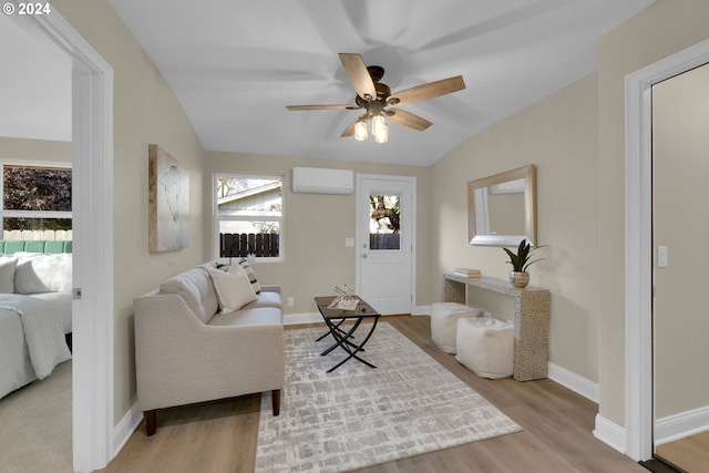 living room featuring ceiling fan, an AC wall unit, vaulted ceiling, and light wood-type flooring