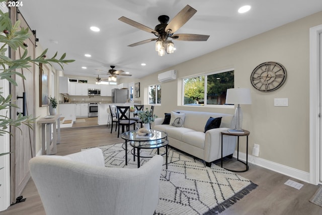 living room featuring an AC wall unit, light hardwood / wood-style floors, and ceiling fan