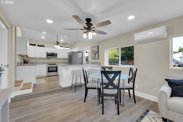 dining area with light hardwood / wood-style floors, a wealth of natural light, a wall mounted air conditioner, and ceiling fan