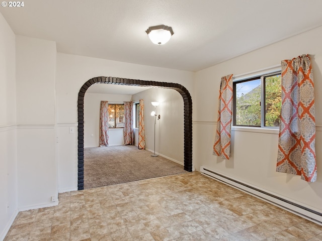 empty room with light colored carpet and a baseboard heating unit